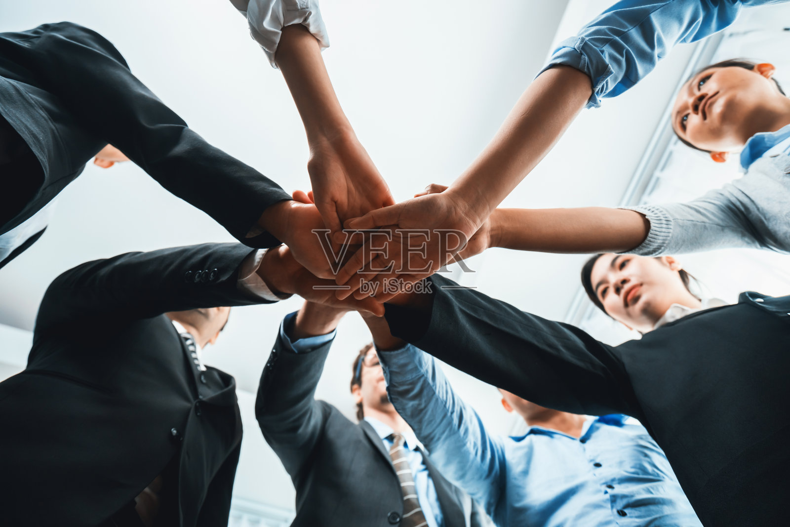 多种族的商务人士一起叠手,形成协同效应。服装照片摄影图片