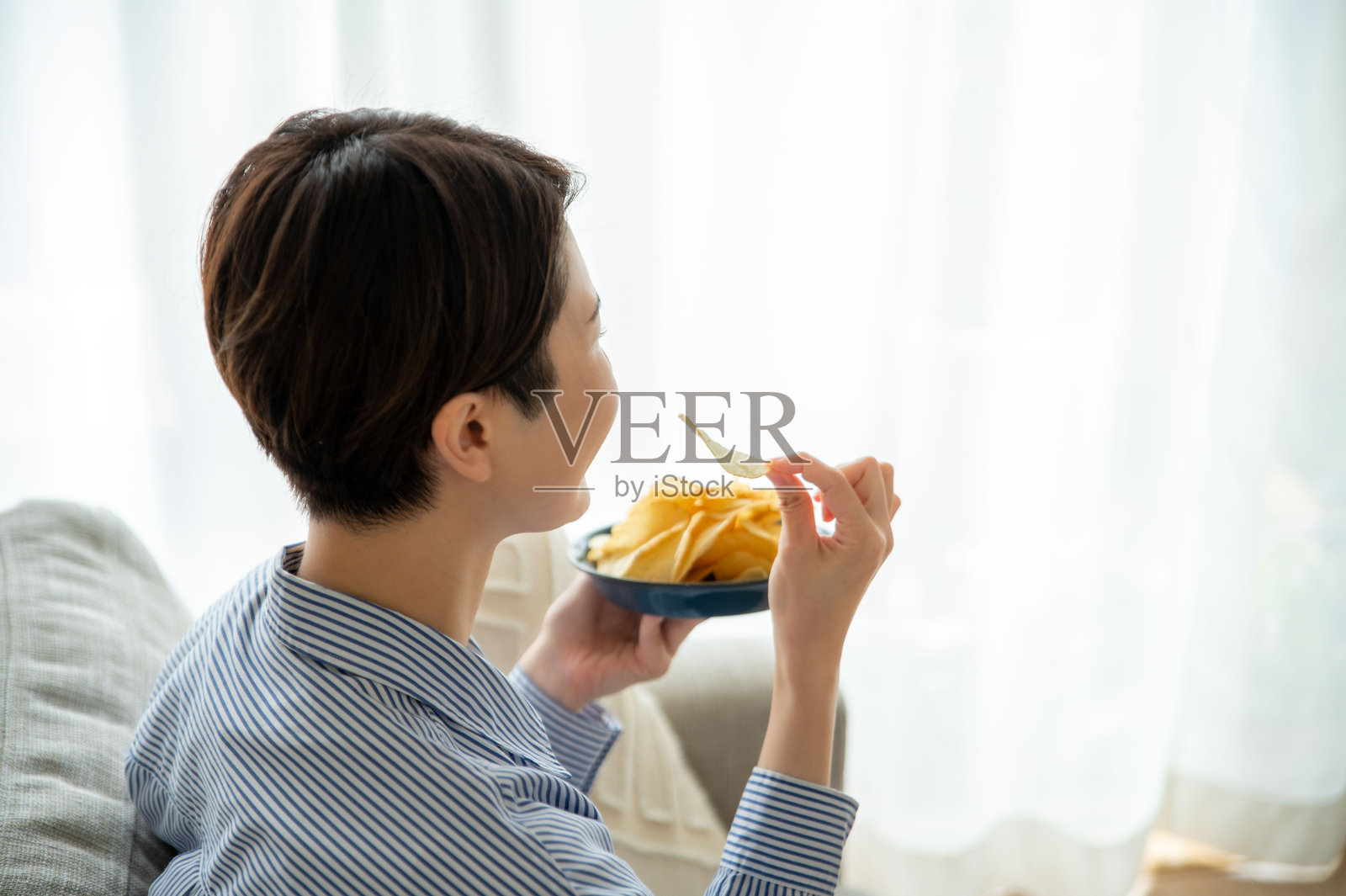 一位手拿薯片的女性照片摄影图片