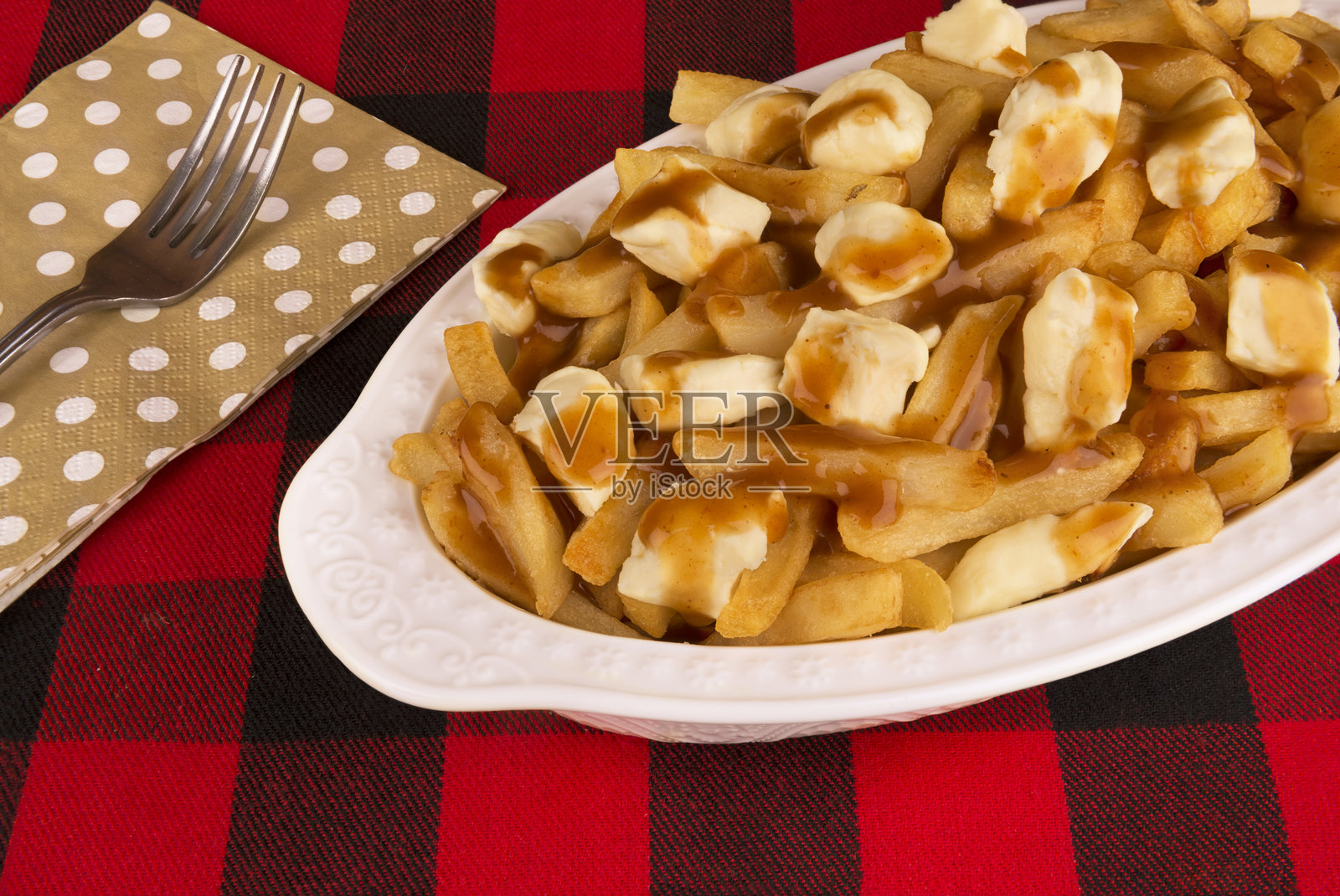 红黑格子桌布上的肉汁薯条。用炸薯条制作的美食。照片摄影图片
