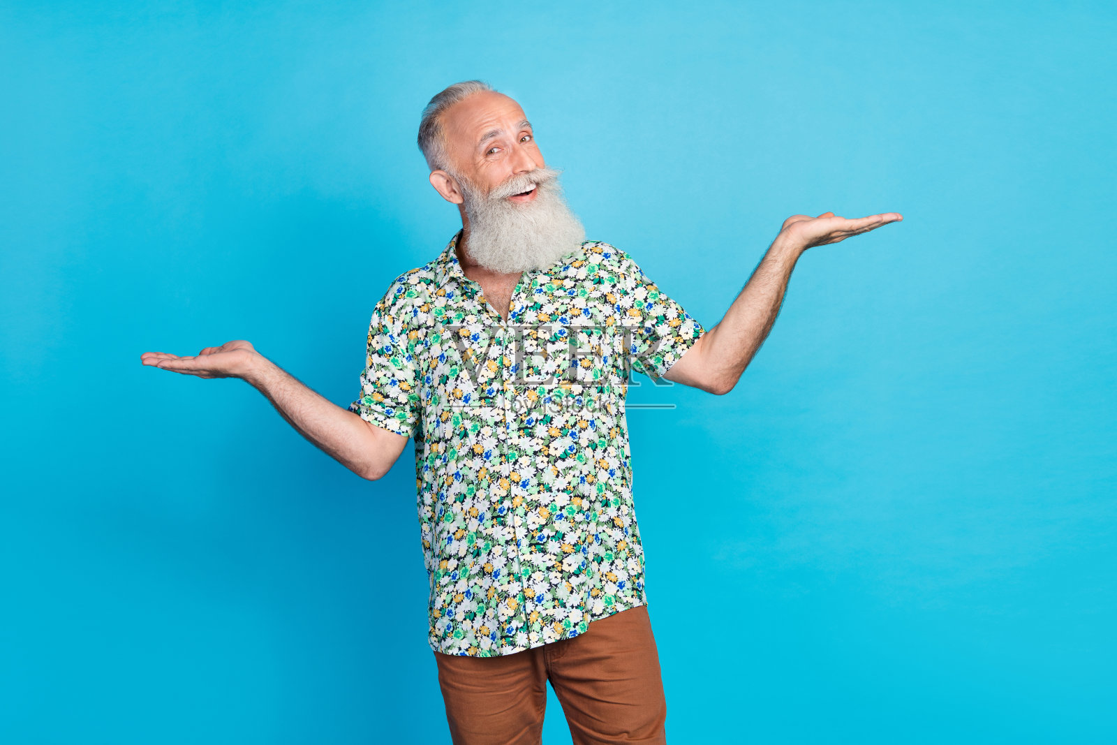 帅气积极的爷爷肖像,双手托着空旷的空间,背景为蓝色。照片摄影图片