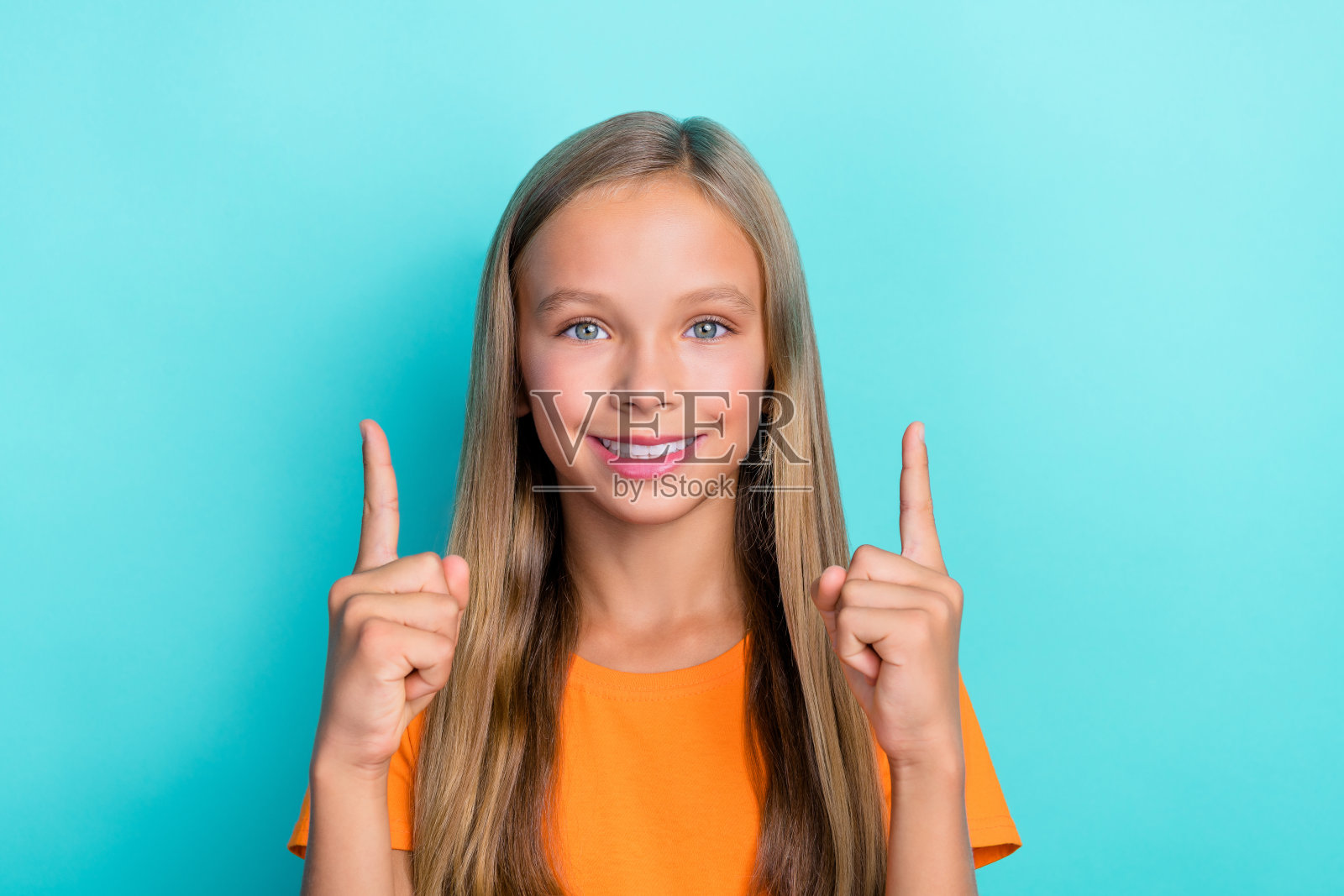 时尚衣着的漂亮积极女孩特写,手臂指向空白区域,反馈酷炫商店促销,背景为青色。照片摄影图片