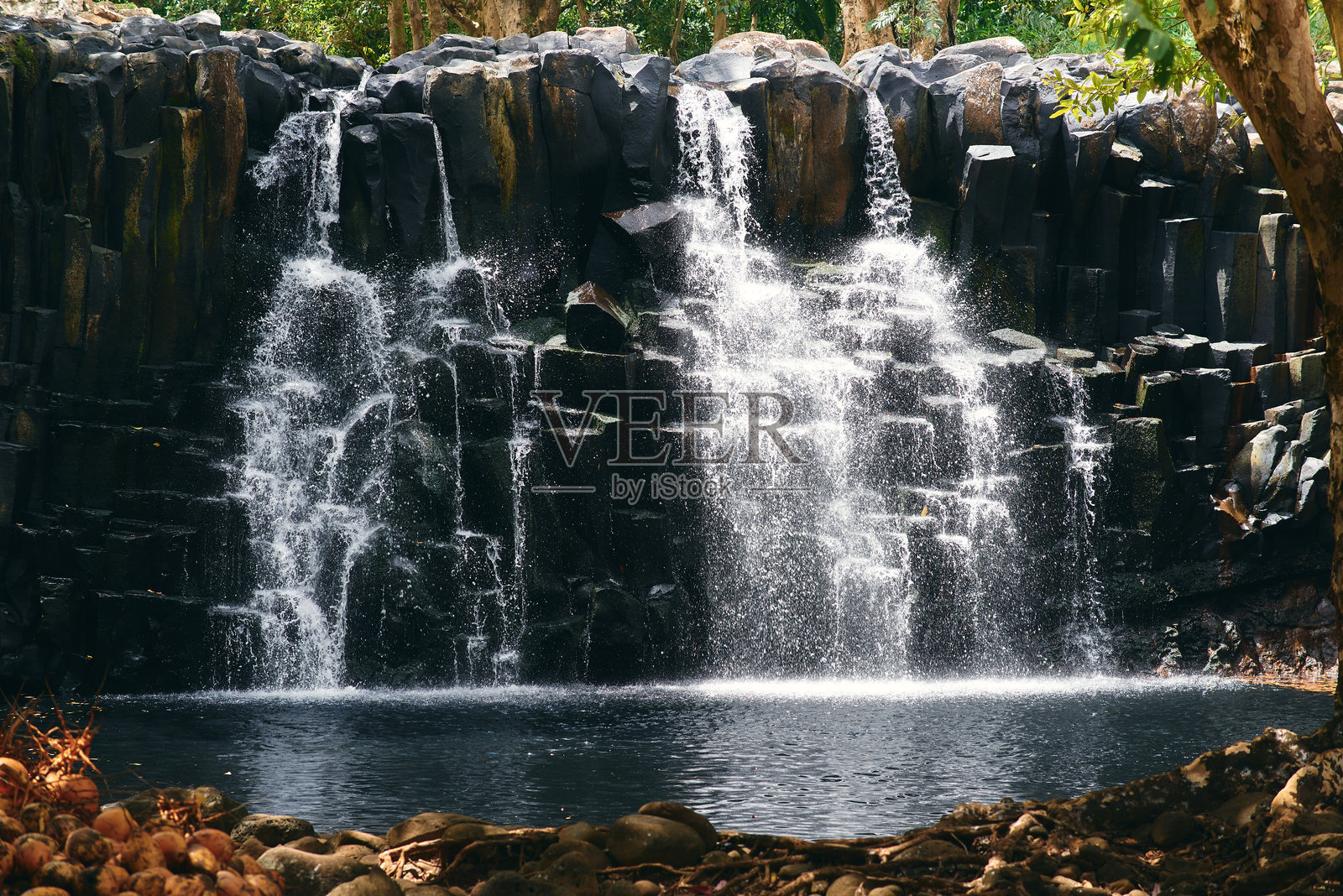 美丽的毛里求斯罗切斯特瀑布,展现出瀑布在崎岖的火山岩石上倾泻而下,四周环绕着郁郁葱葱的热带绿植。照片摄影图片