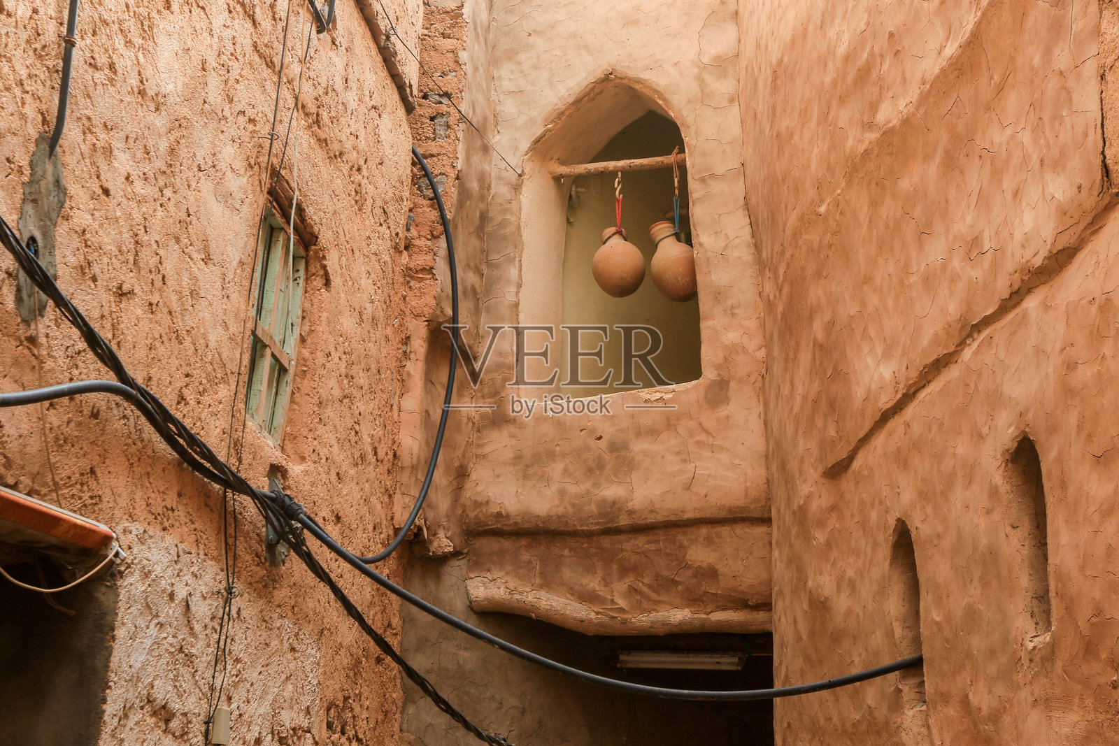 阿曼村庄迷人的狭窄小巷,展现传统建筑和悬挂的陶器,沐浴在午后的阳光中照片摄影图片