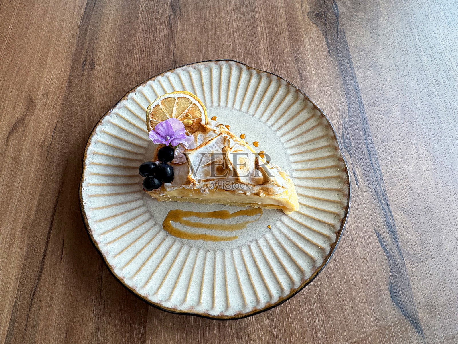 美丽的优质柠檬奶酪奶油层烤挞蛋糕,上面装饰有蓝莓花,呈3D形状,放在木桌上的盘子里,适合清真饮食的亚洲甜点,西式咖啡馆糕点菜单。照片摄影图片