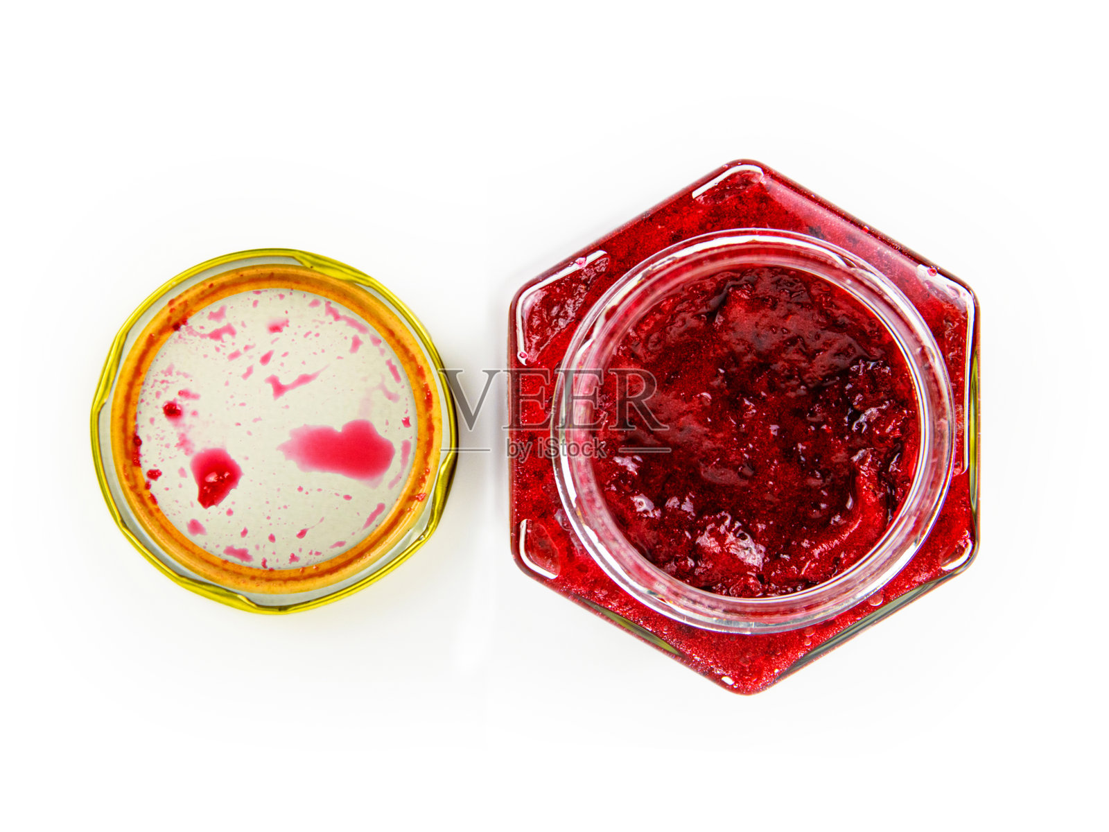 一个打开的六角形玻璃罐,里面装着自制的红醋栗果酱或蔓越莓果酱,旁边有一个金色的盖子。新鲜制作的野生浆果果冻。留白空间。白色背景上的孤立视图。俯视图。照片摄影图片