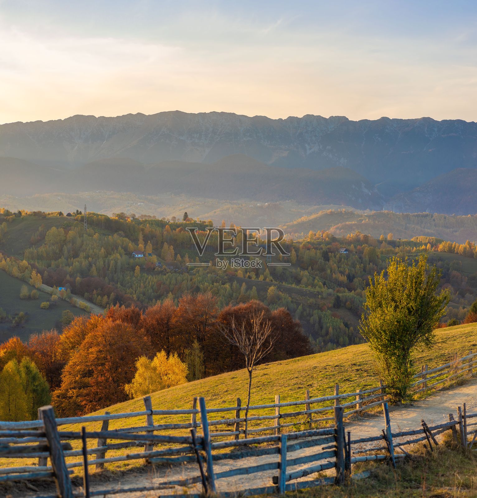 秋天的山丘和山脉在日落时分,配有乡村风格的围栏。照片摄影图片