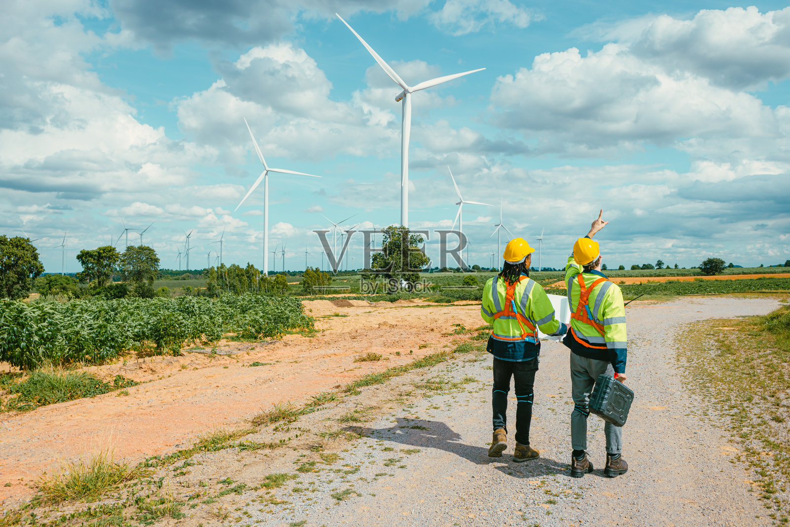 工程师在户外风力涡轮机清洁能源发电站背景下工作,工人团队为风电场提供服务。照片摄影图片