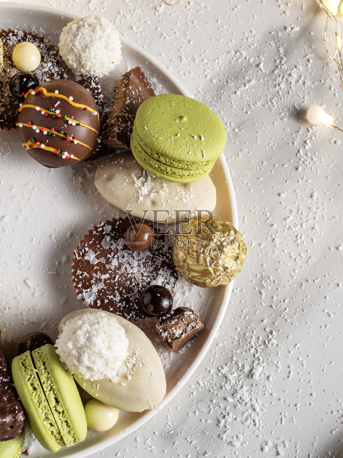 巧克力圣诞背景下的马卡龙。巧克力的选择。盘子里的奢华巧克力。巧克力松露组合。奢华巧克力和马卡龙的特写。巧克力盘。照片摄影图片