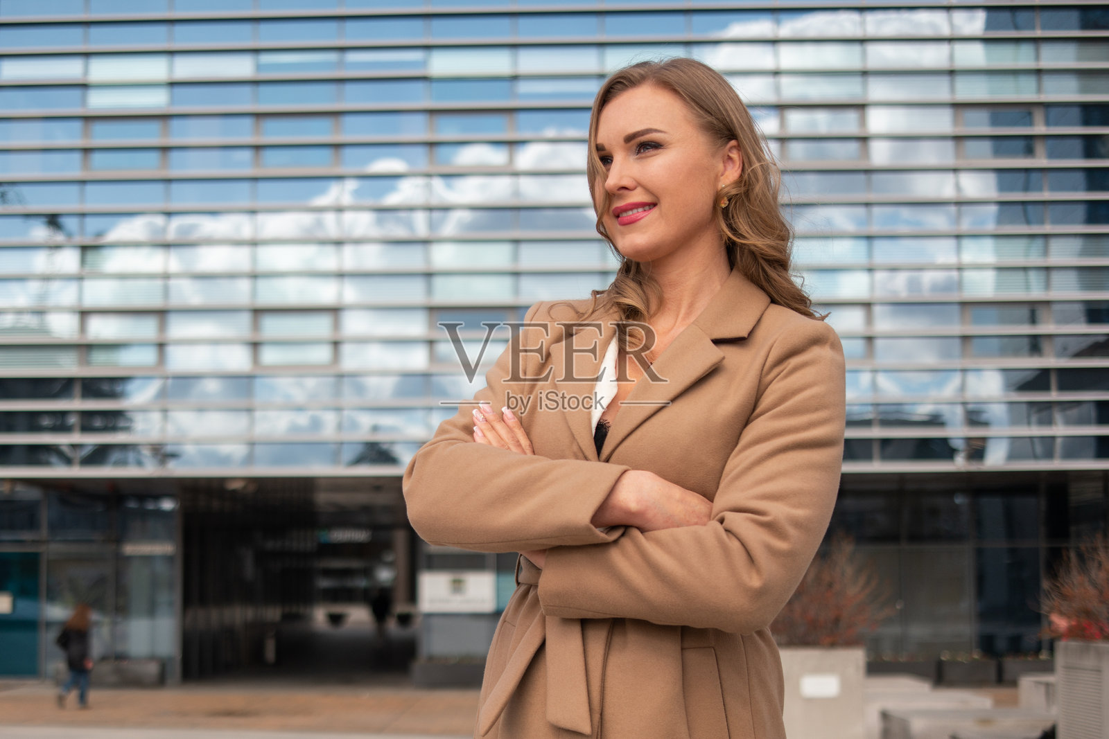自信的女商人微笑着,双臂交叉站在办公大楼前照片摄影图片