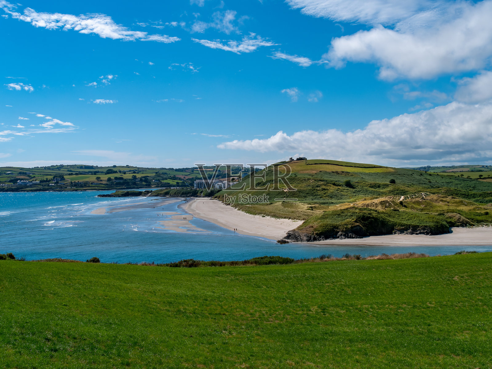 因希多尼岛的绿色山丘和著名的爱尔兰海滩在阳光明媚的夏日。清澈的蓝天和白云在爱尔兰海岸上方。爱尔兰夏季风景。靠近水域的绿色草地。照片摄影图片