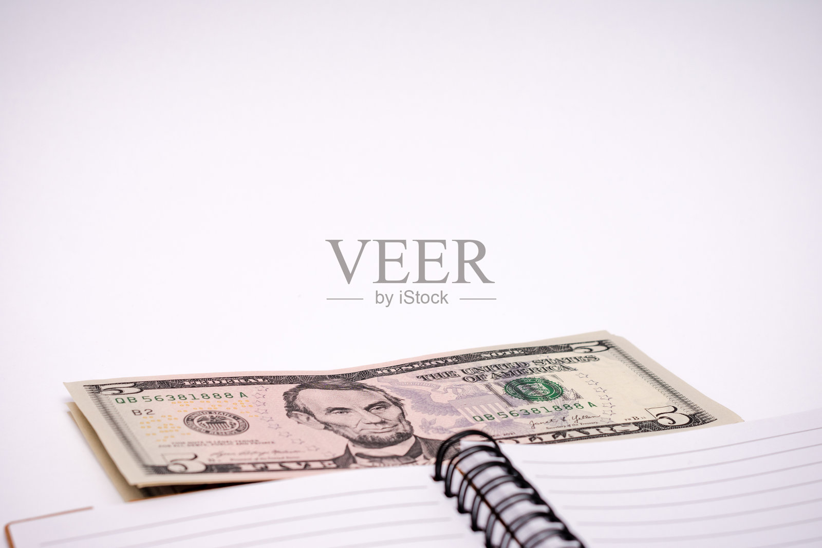 五美元钞票放在一个螺旋笔记本上照片摄影图片