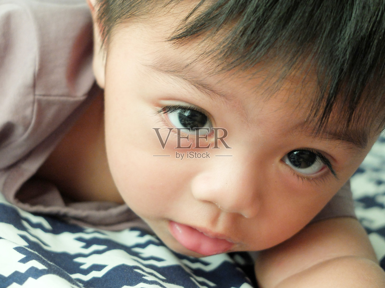 可爱男婴在家床上躺着的特写肖像照片摄影图片