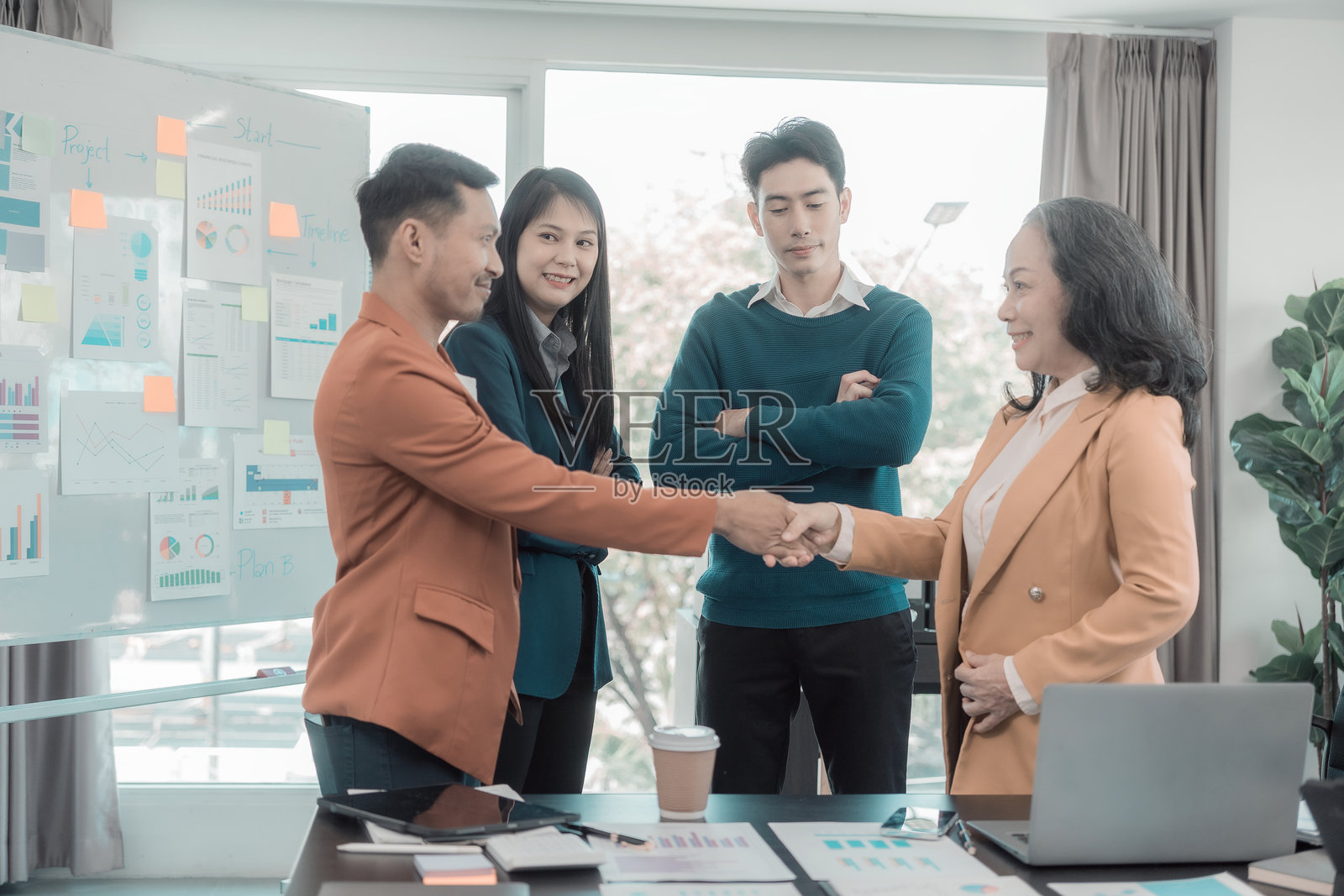 商人们在谈判商业交易时握手。争议和调解的储存库。商业战略上的团队合作。会议讨论了绩效图表和图形。照片摄影图片