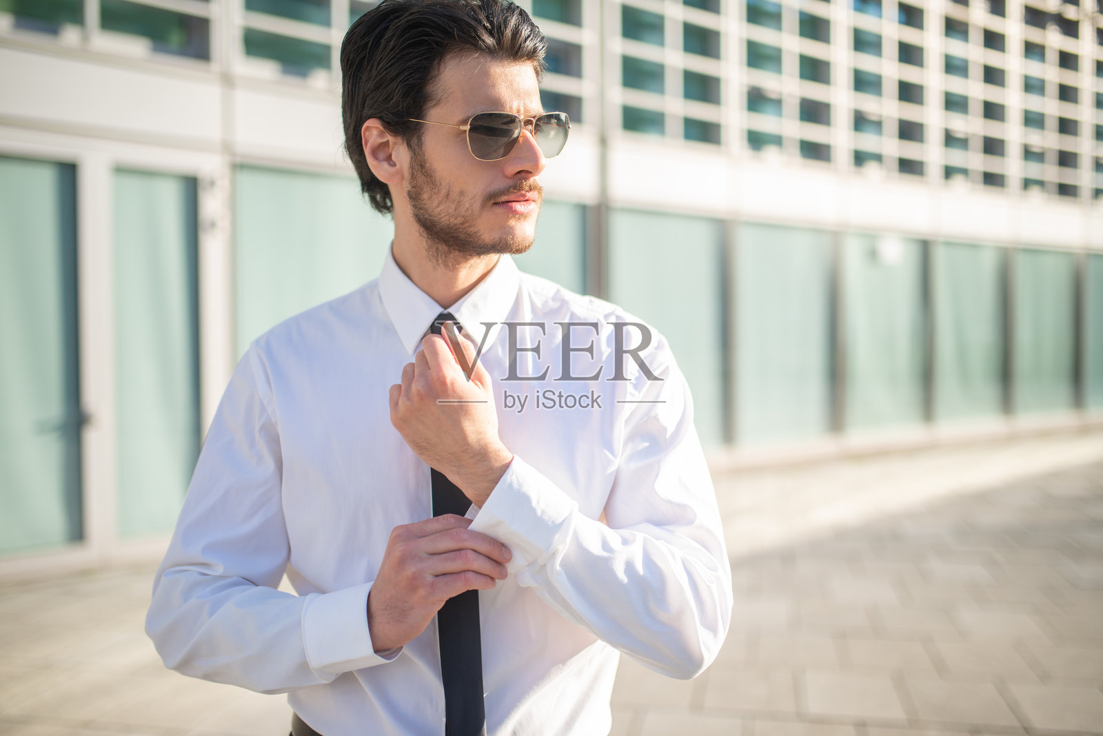 商人在现代办公大楼前整理领带照片摄影图片