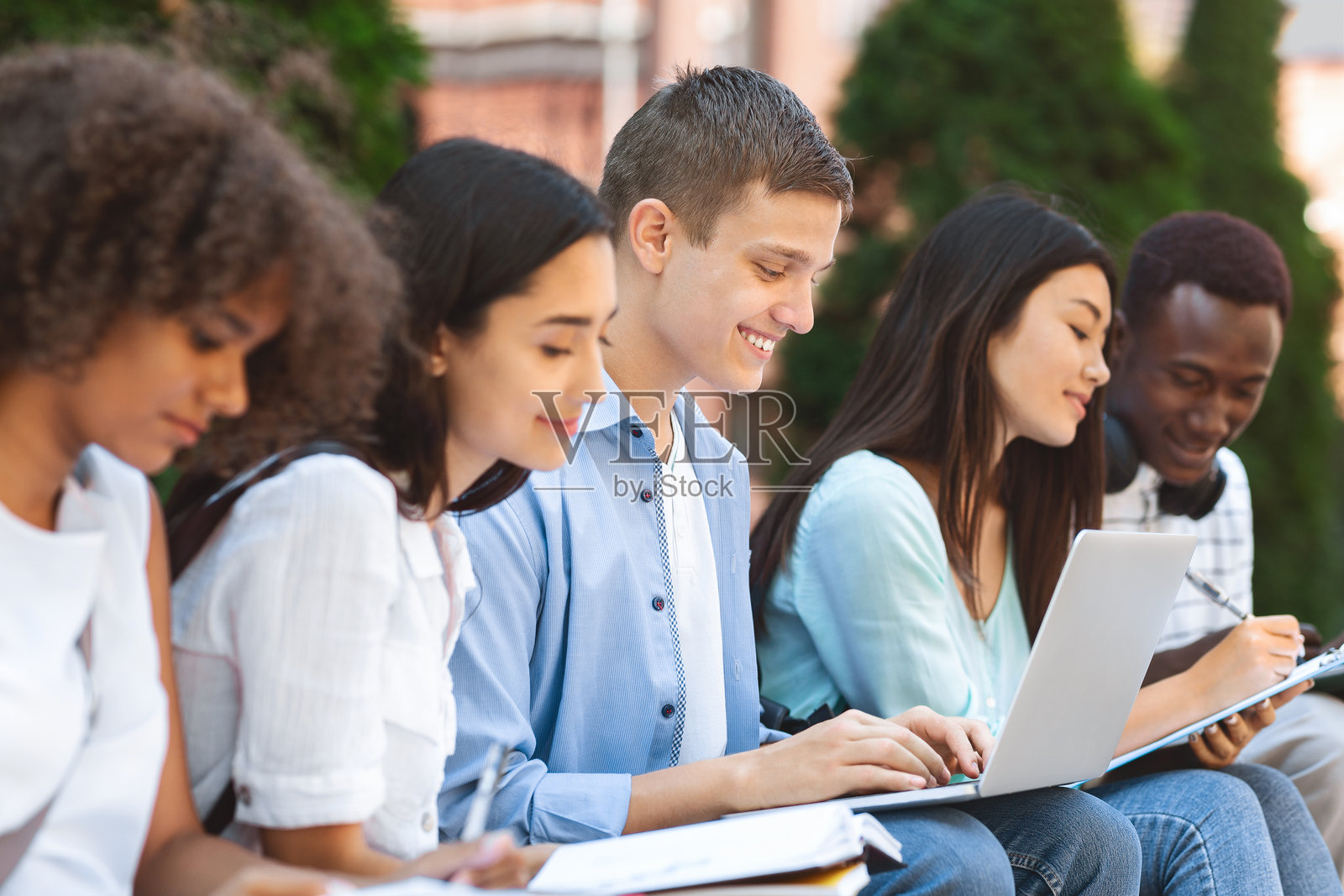 多民族学生在校园长椅上准备上课照片摄影图片