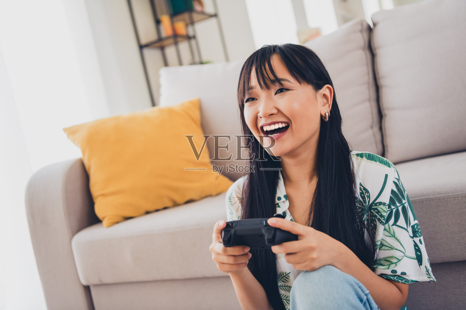 愉快的女性穿着T恤,在公寓的客厅里享受周末,玩着PlayStation。照片摄影图片