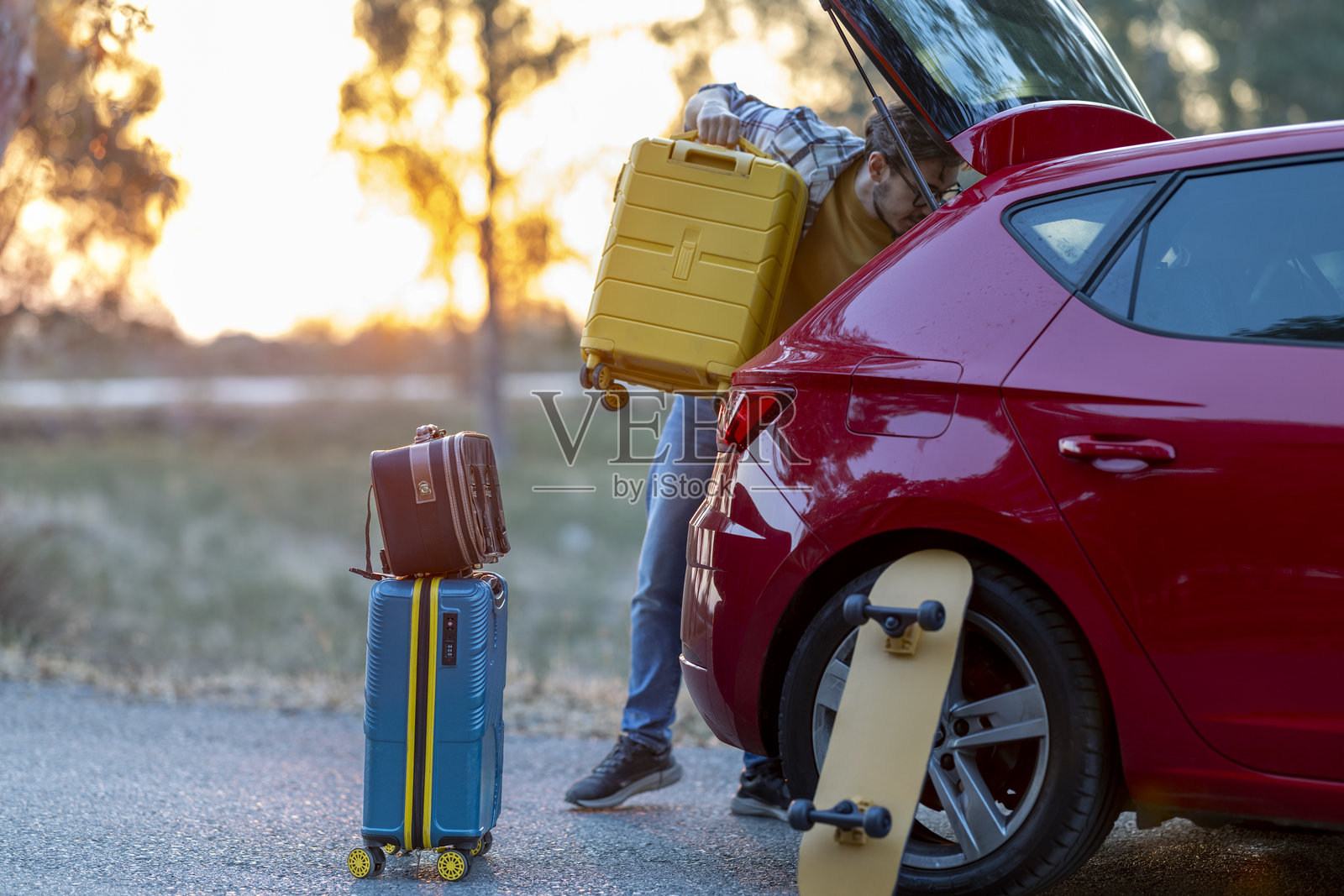 准备出发的男人发现汽车的行李在行李箱里。照片摄影图片
