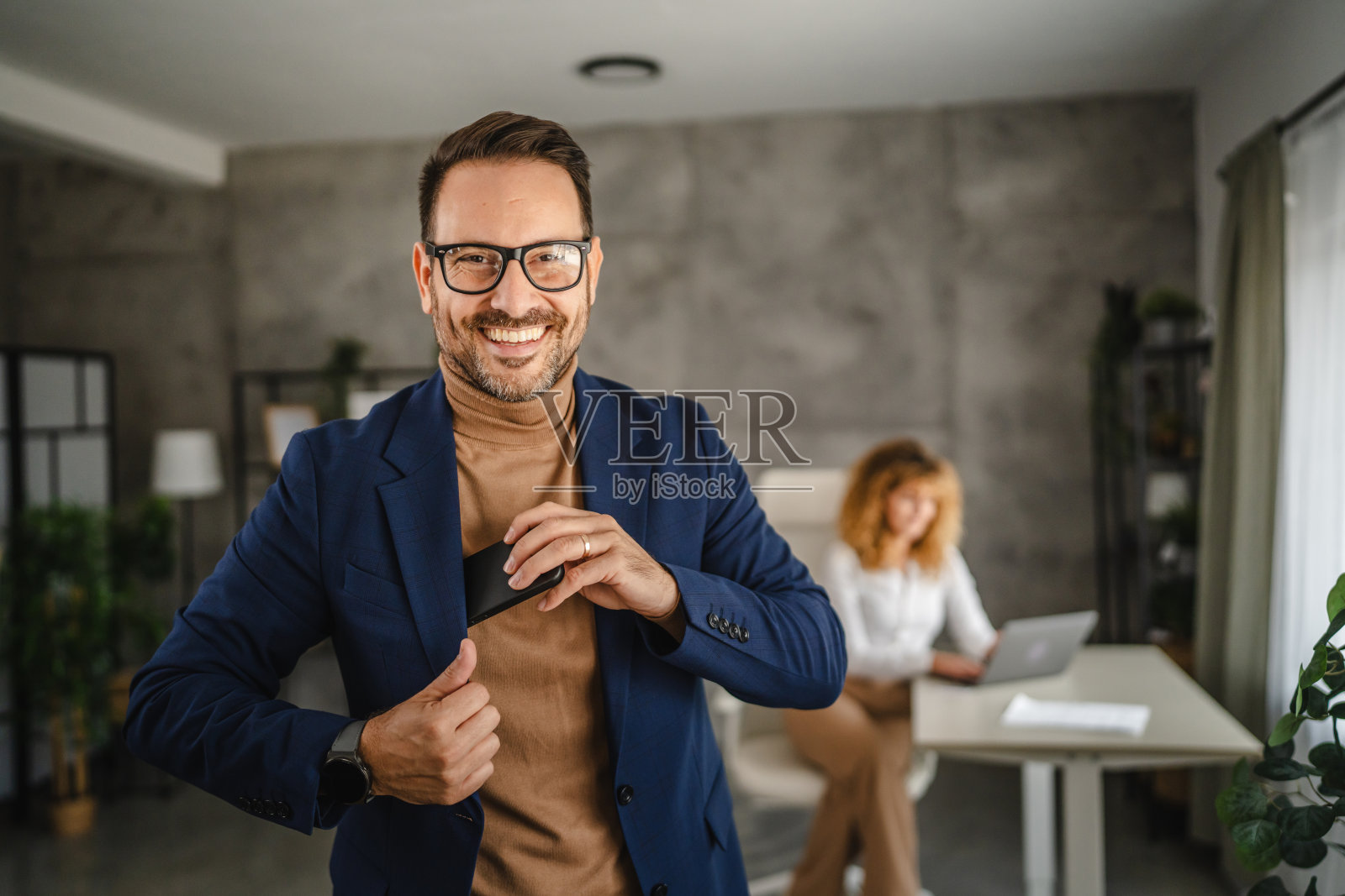 英俊商人的肖像将手机放入西装口袋中照片摄影图片