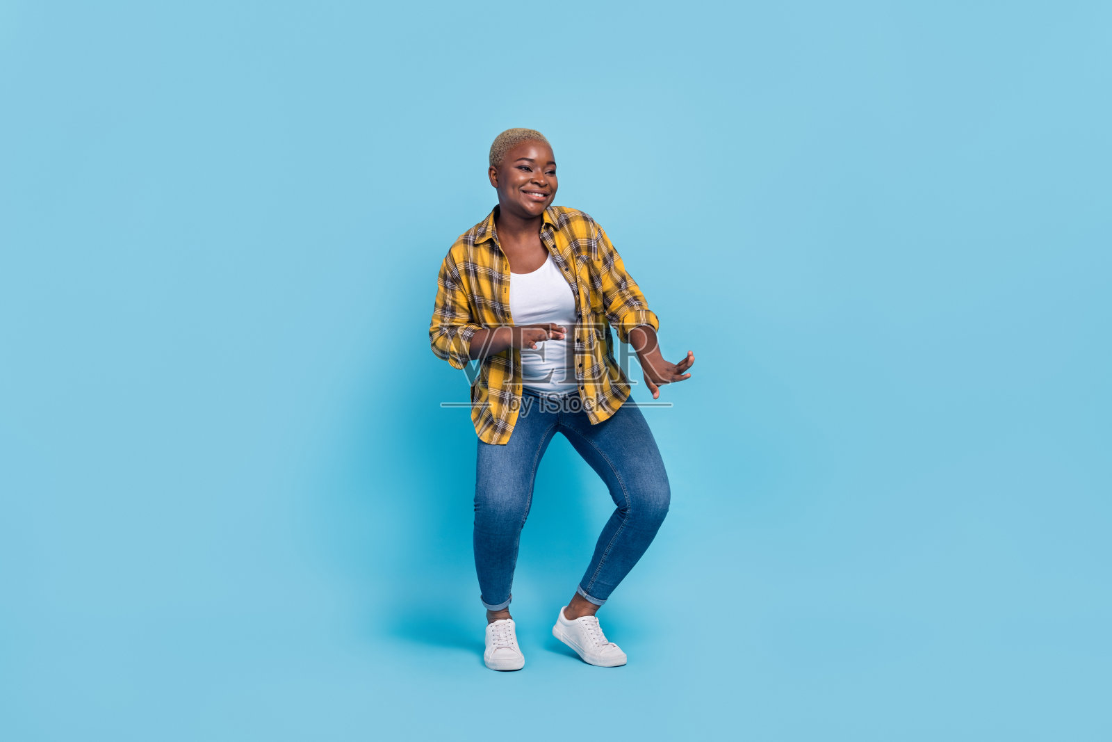穿着格子衬衫的迷人女士在蓝色背景下微笑跳舞的全身照片照片摄影图片