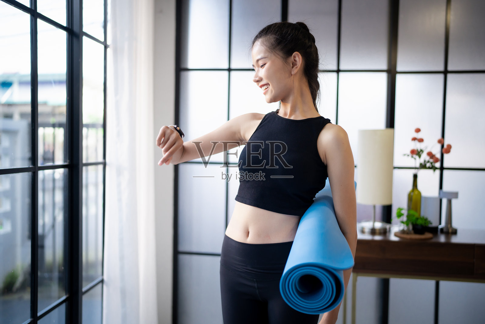 运动中的亚洲女性穿着运动服,手腕上佩戴健康应用程序的智能手表,训练后在瑜伽垫上。照片摄影图片