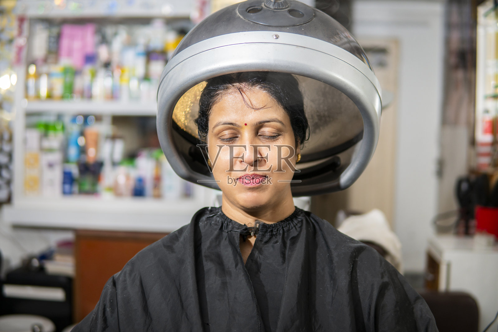 印度女性在发廊接受蒸汽护发治疗。照片摄影图片