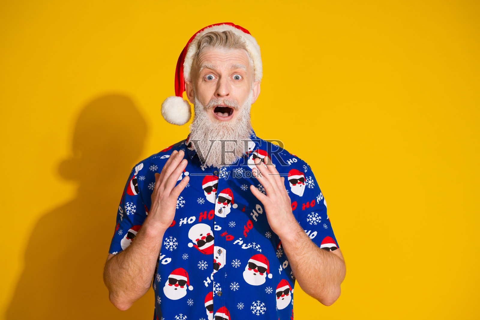 现代时尚圣诞老人紧张地凝视空旷的空间,穿着新年圣诞印花衬衫,背景为黄色。照片摄影图片