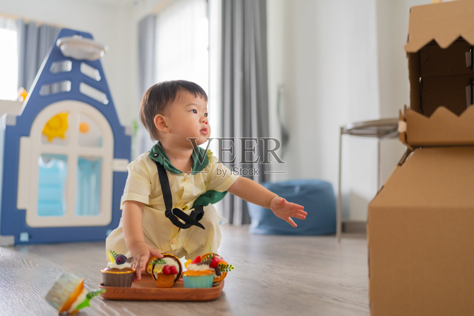 快乐的亚洲男婴学习走路,练习平衡身体,在家居室内背景中迈出第一步,他对周围的一切充满好奇,四处玩耍。照片摄影图片