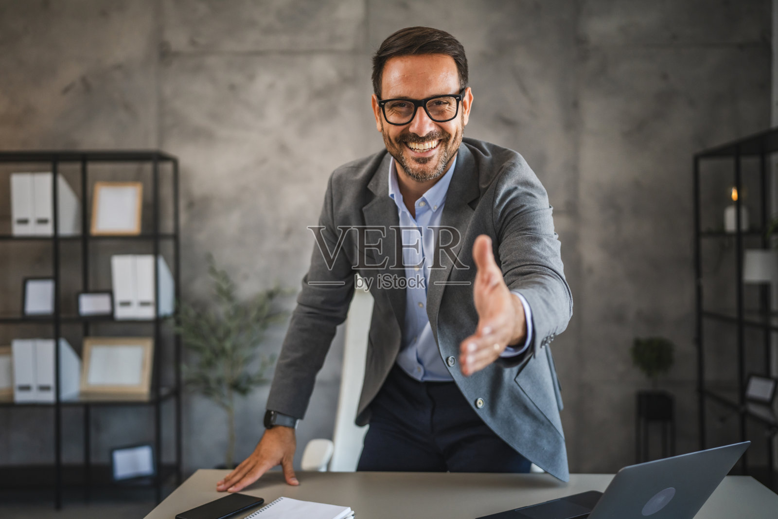 身穿西装的商人伸出手,热情欢迎并建立联系照片摄影图片