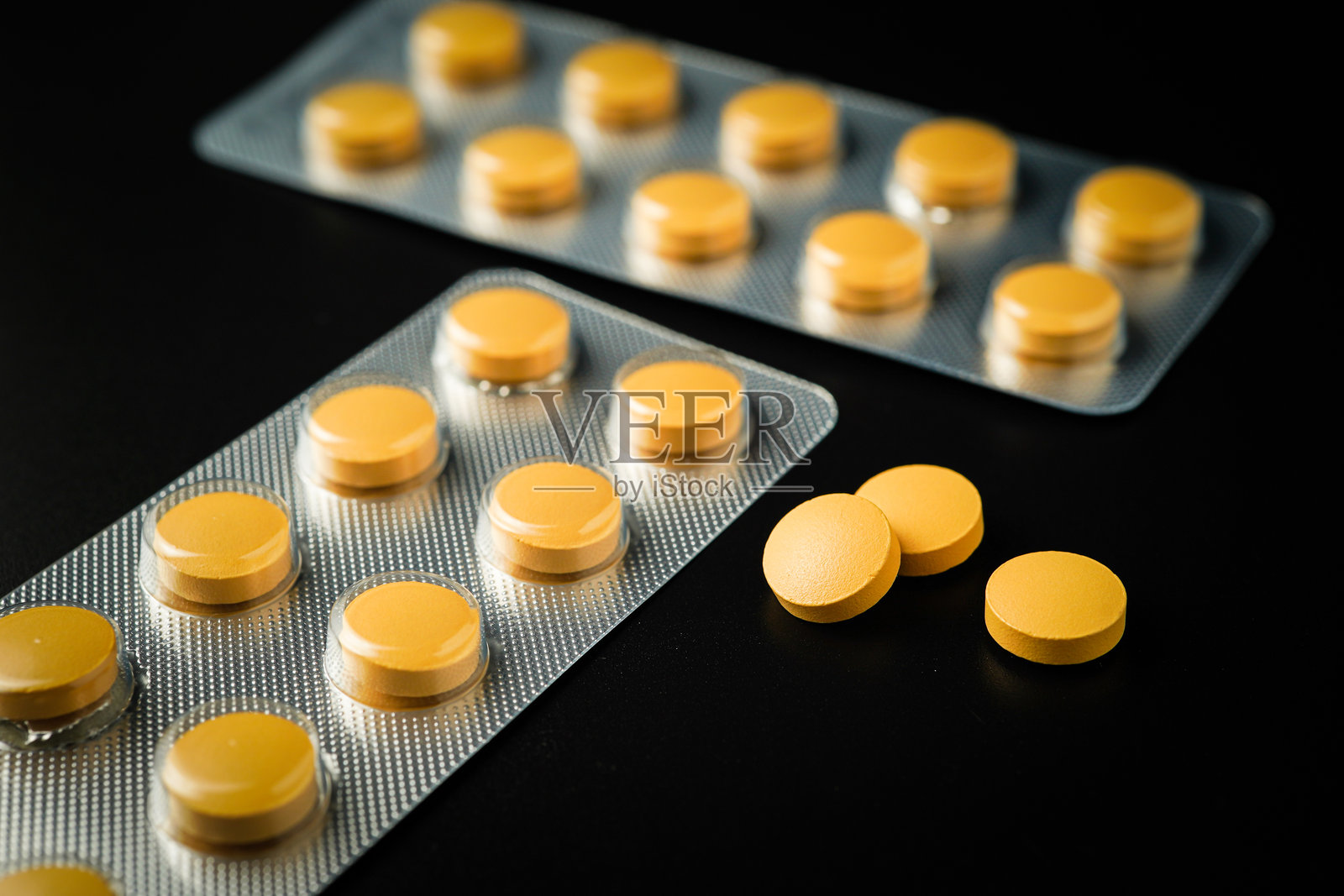退烧止痛药片 棕黄色药片在黑色背景下的泡罩包装中照片摄影图片