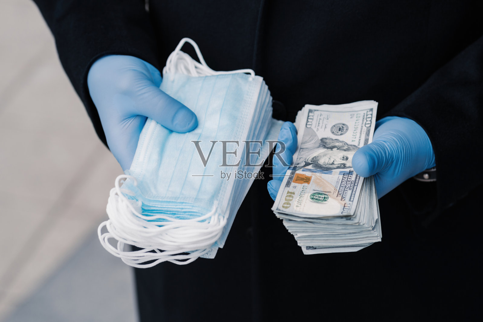 戴着蓝色手套的手拿着口罩和一叠美元钞票,健康成本概念照片摄影图片