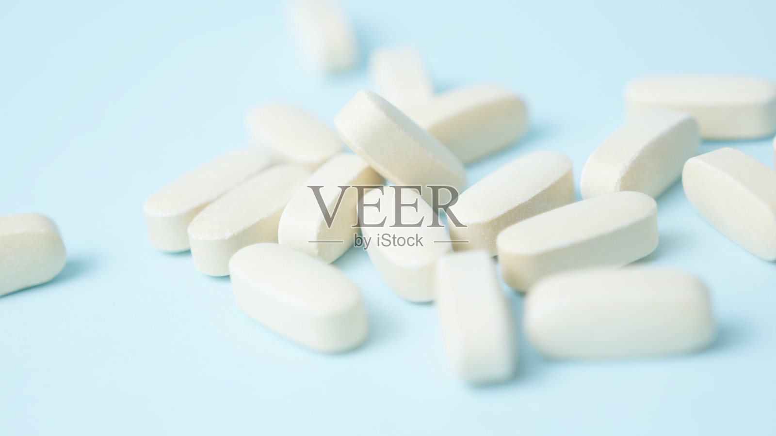 一堆白色药片在浅蓝色背景上。照片摄影图片