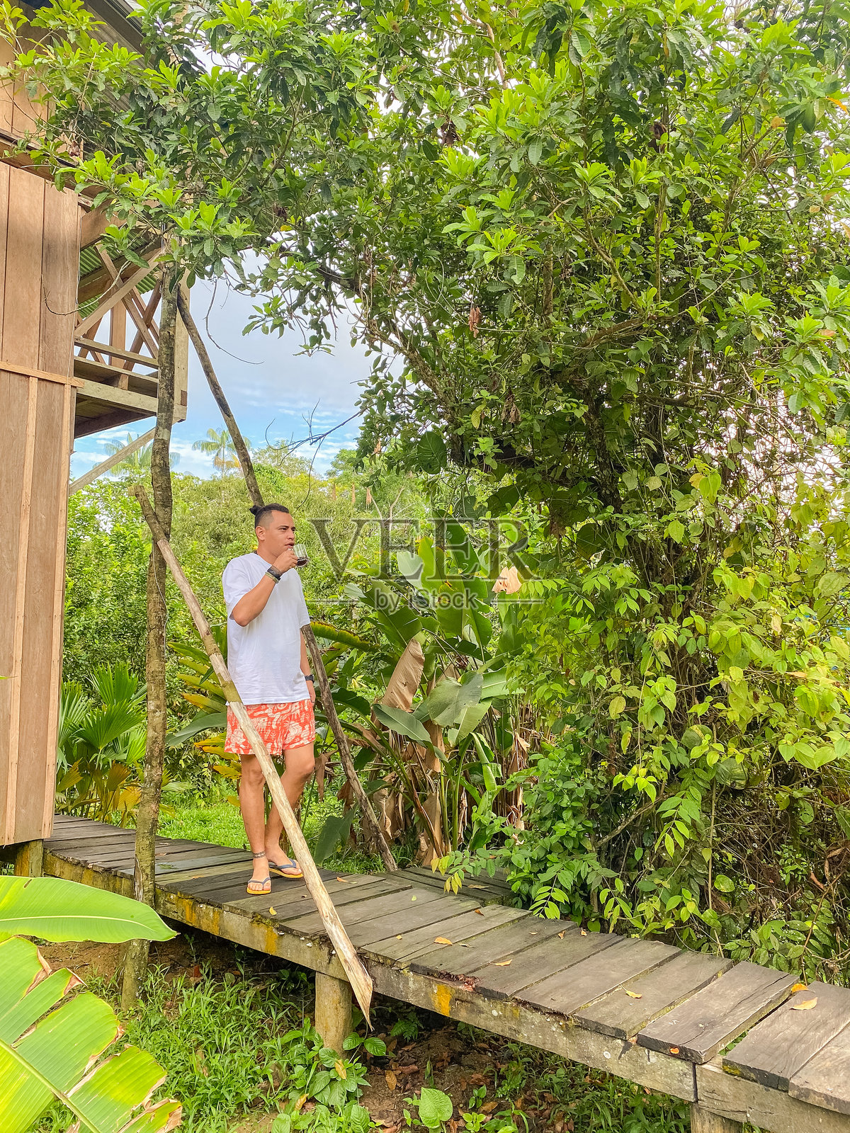 旅行者在郁郁葱葱的热带环境中,享受着木栈道上的一杯咖啡照片摄影图片