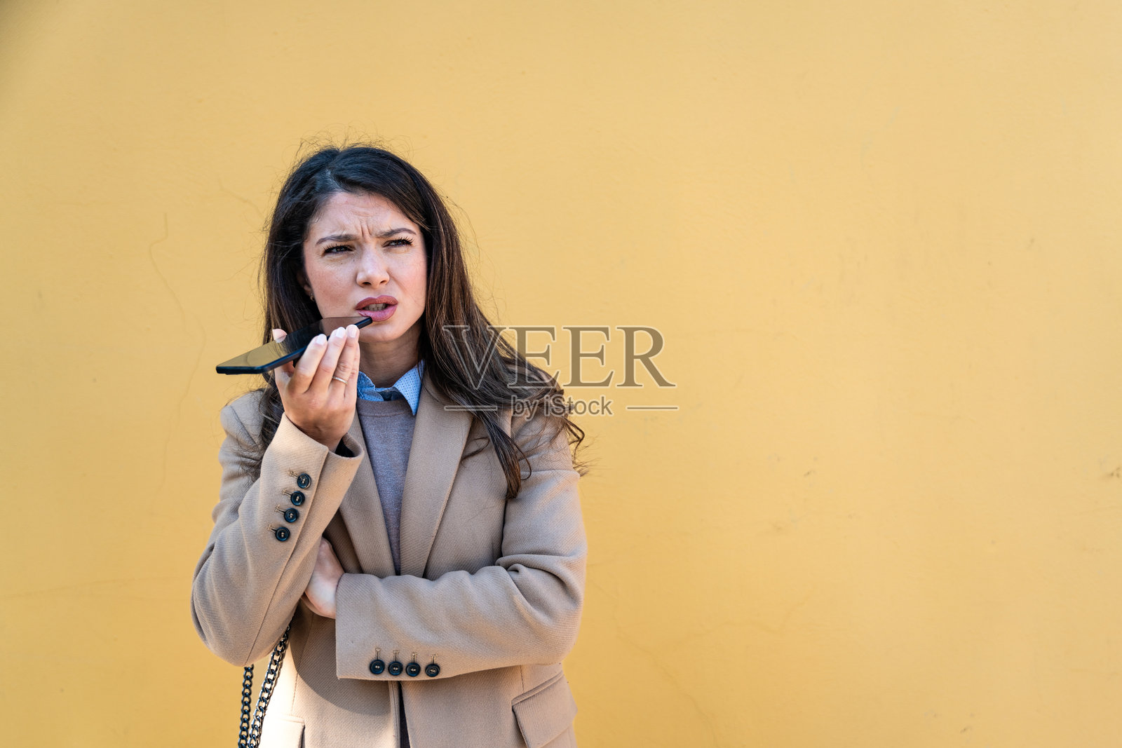 年轻女商人在城市街道上穿着正式服装等待同事去午餐休息时使用智能手机。时尚的女性在下班后使用电话进行在线约会。照片摄影图片