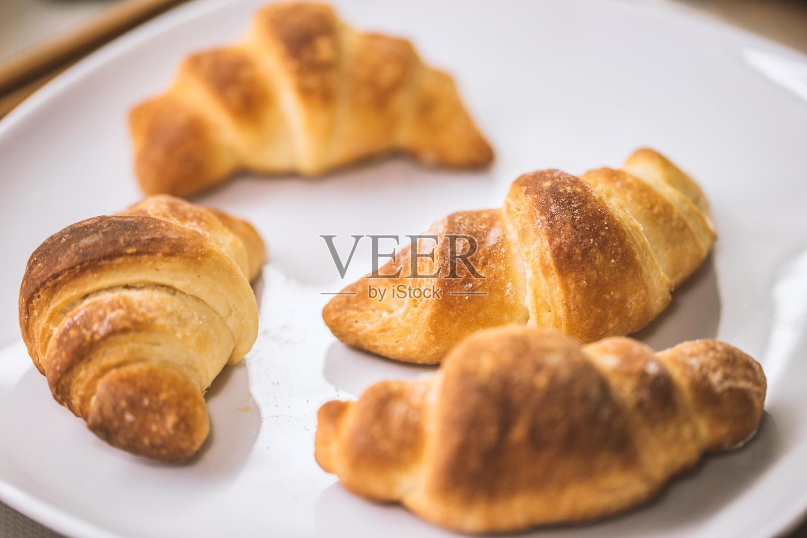 四个可颂面包放在白色盘子上照片摄影图片