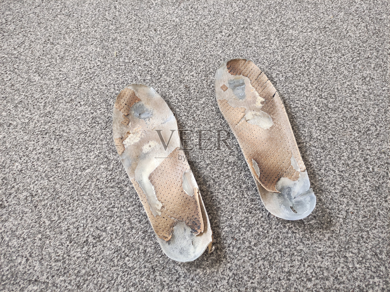 两双破旧的矫形鞋垫放在灰色表面上照片摄影图片