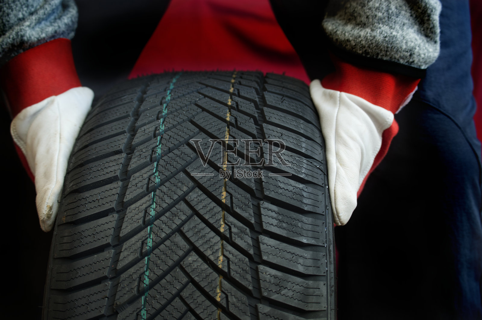 机械师戴着防护手套在车间检查重型轮胎照片摄影图片