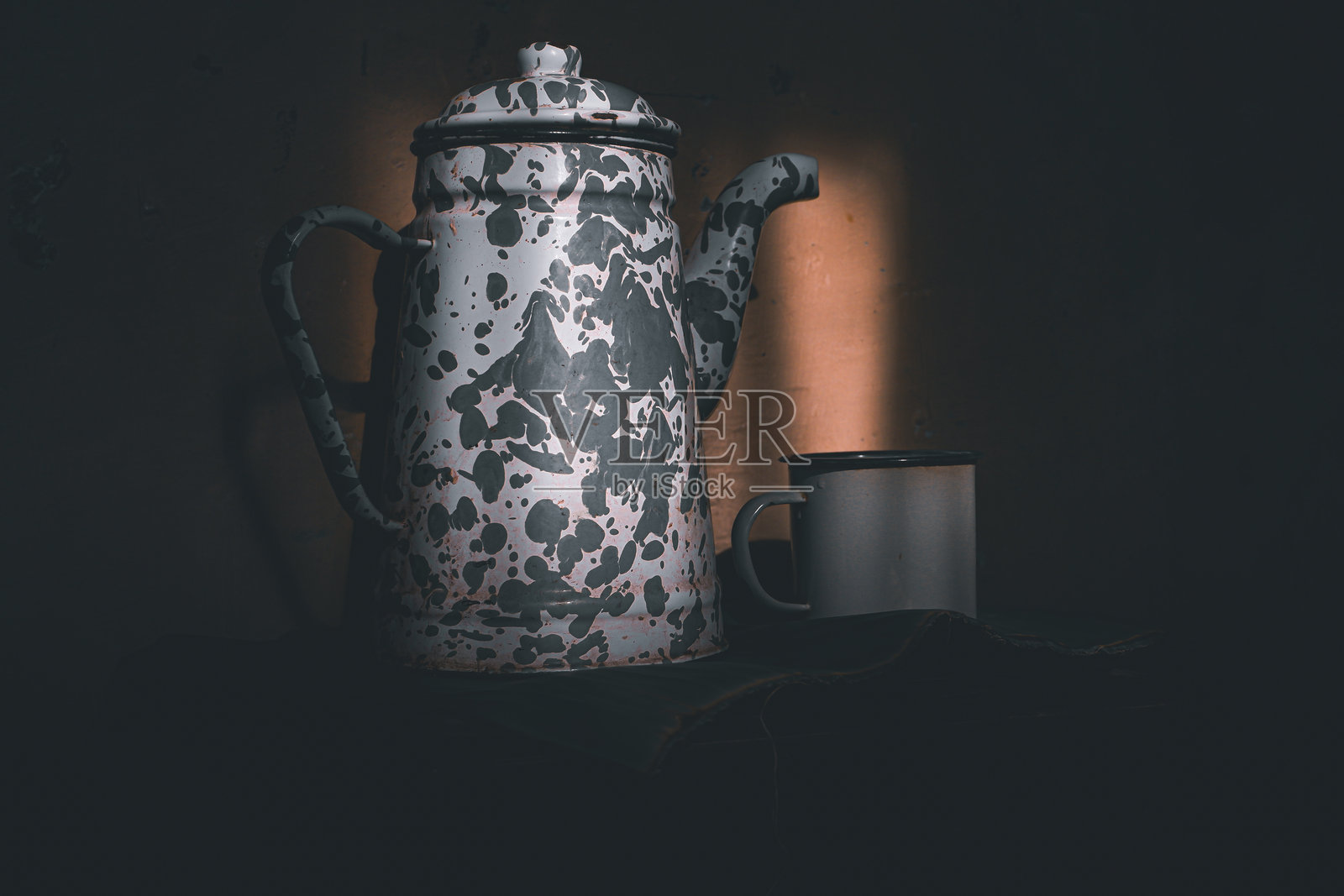 在昏暗的地方,一只搪瓷杯和一个茶壶照片摄影图片