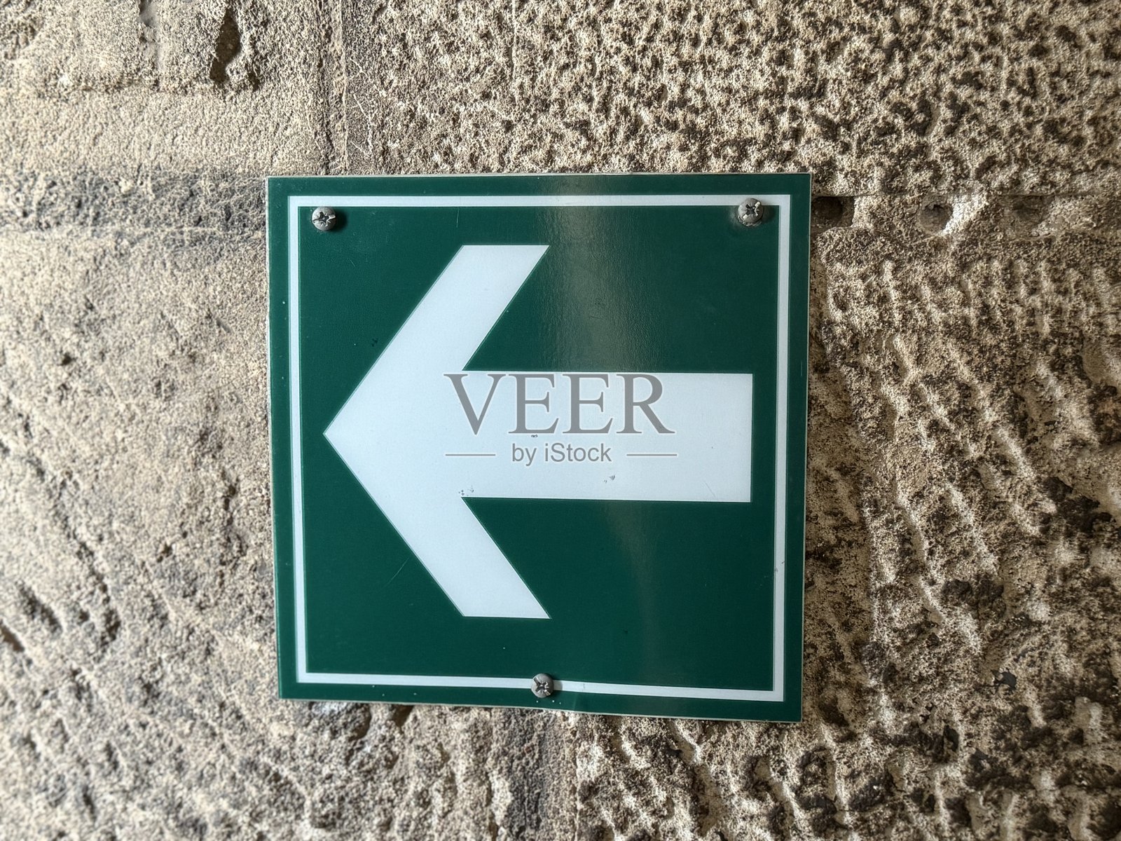 绿色标志上的白色箭头指向左侧照片摄影图片