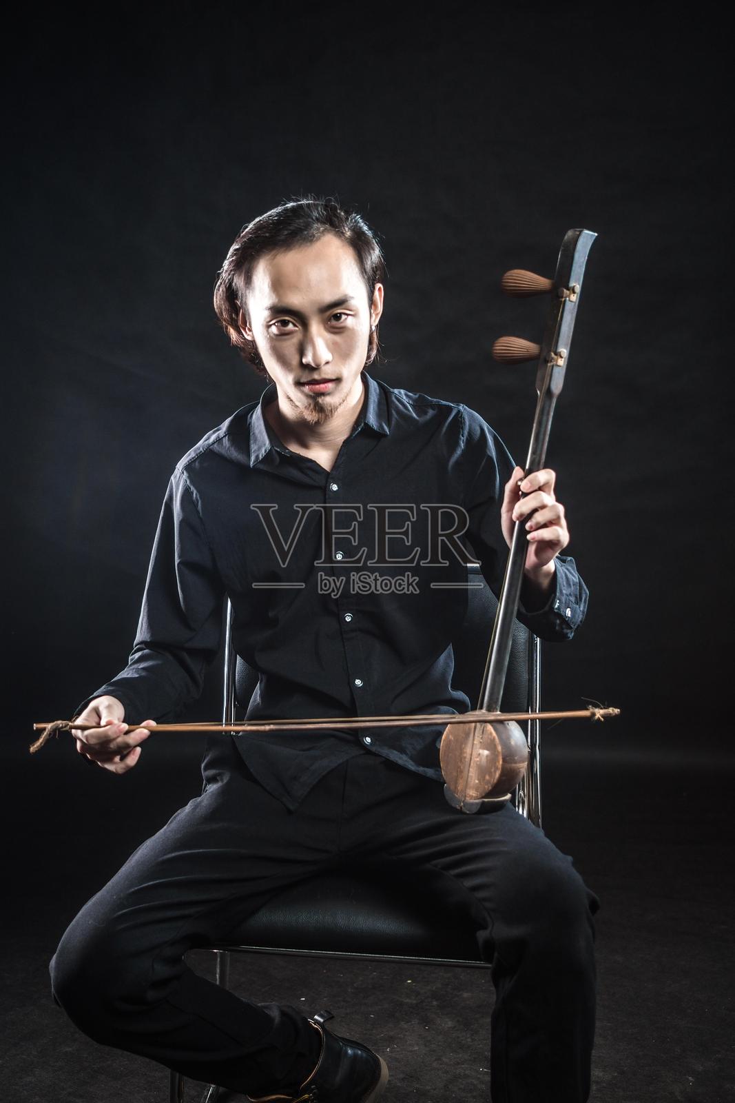 年轻男子演奏中国传统乐器二胡的肖像照片摄影图片