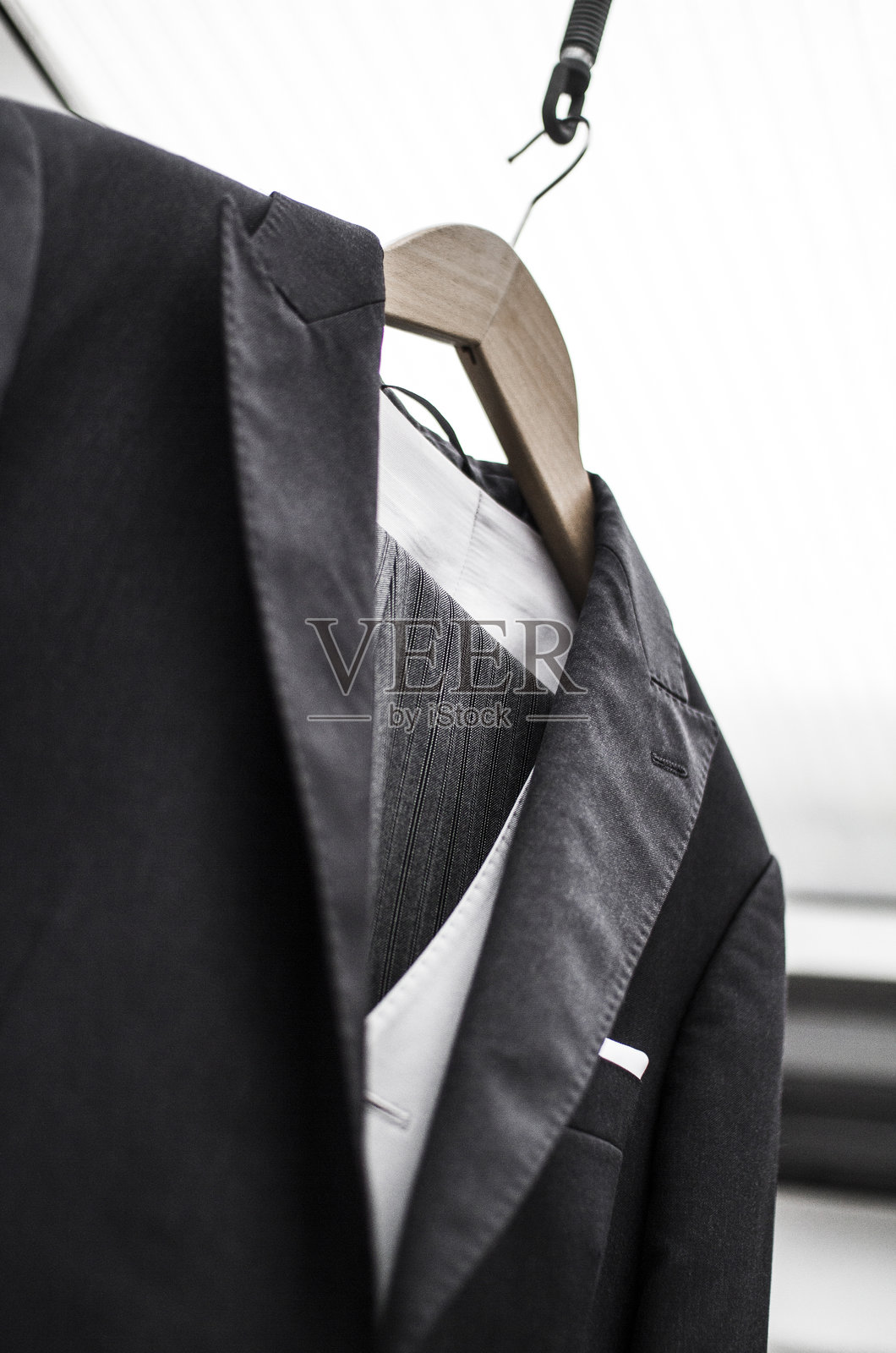 优雅的黑色西装挂在木质衣架上,置于时尚现代的环境中照片摄影图片
