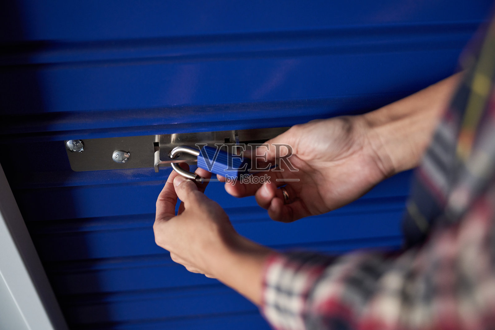 漂亮的女性手握着一个蓝色的挂锁,正在将其锁上照片摄影图片