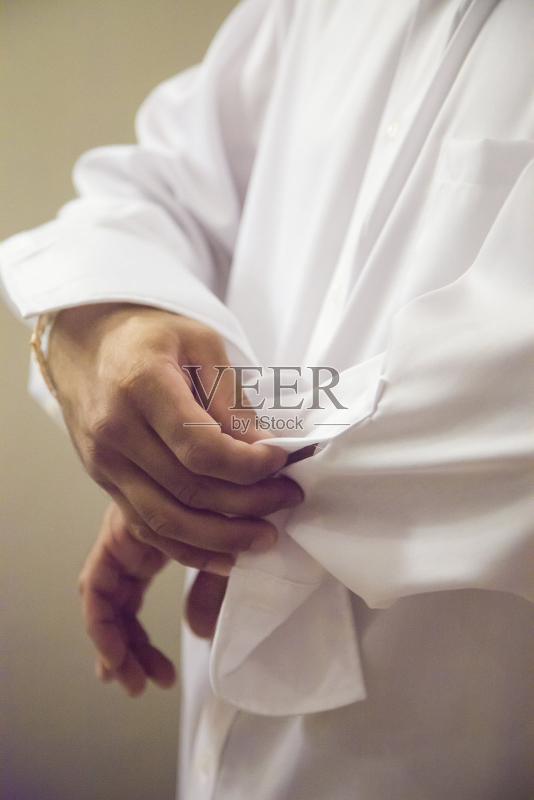 一个人在柔和的室内光线下调整白色衣物,正值傍晚时分。照片摄影图片