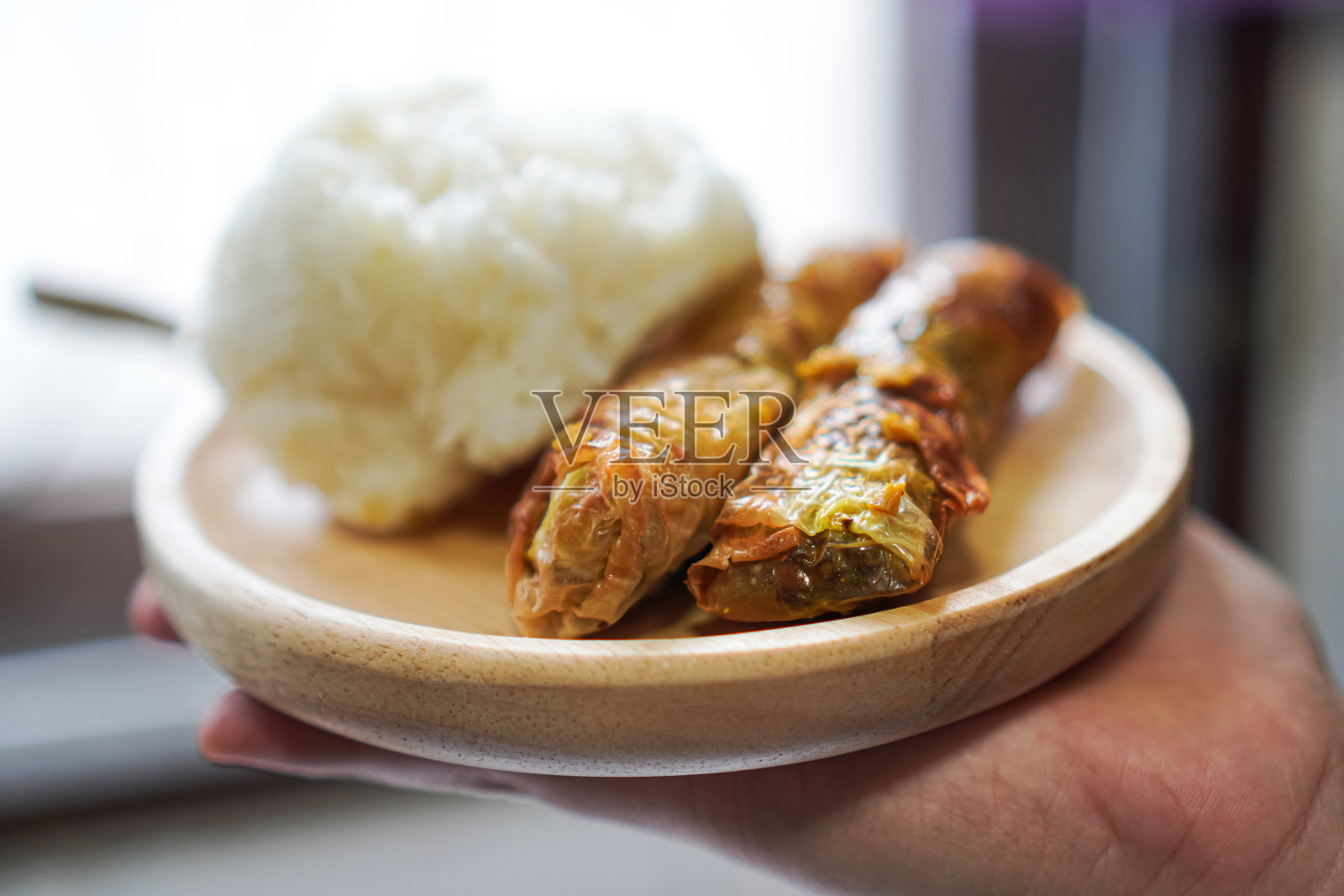 一个侧面图显示了一个木制盘子上的素食菜单,包括糯米和素食香肠。照片摄影图片