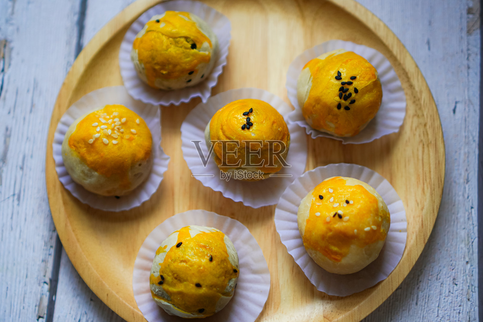 上图为木盘上撒有白芝麻和黑芝麻的咸蛋豆饼。照片摄影图片