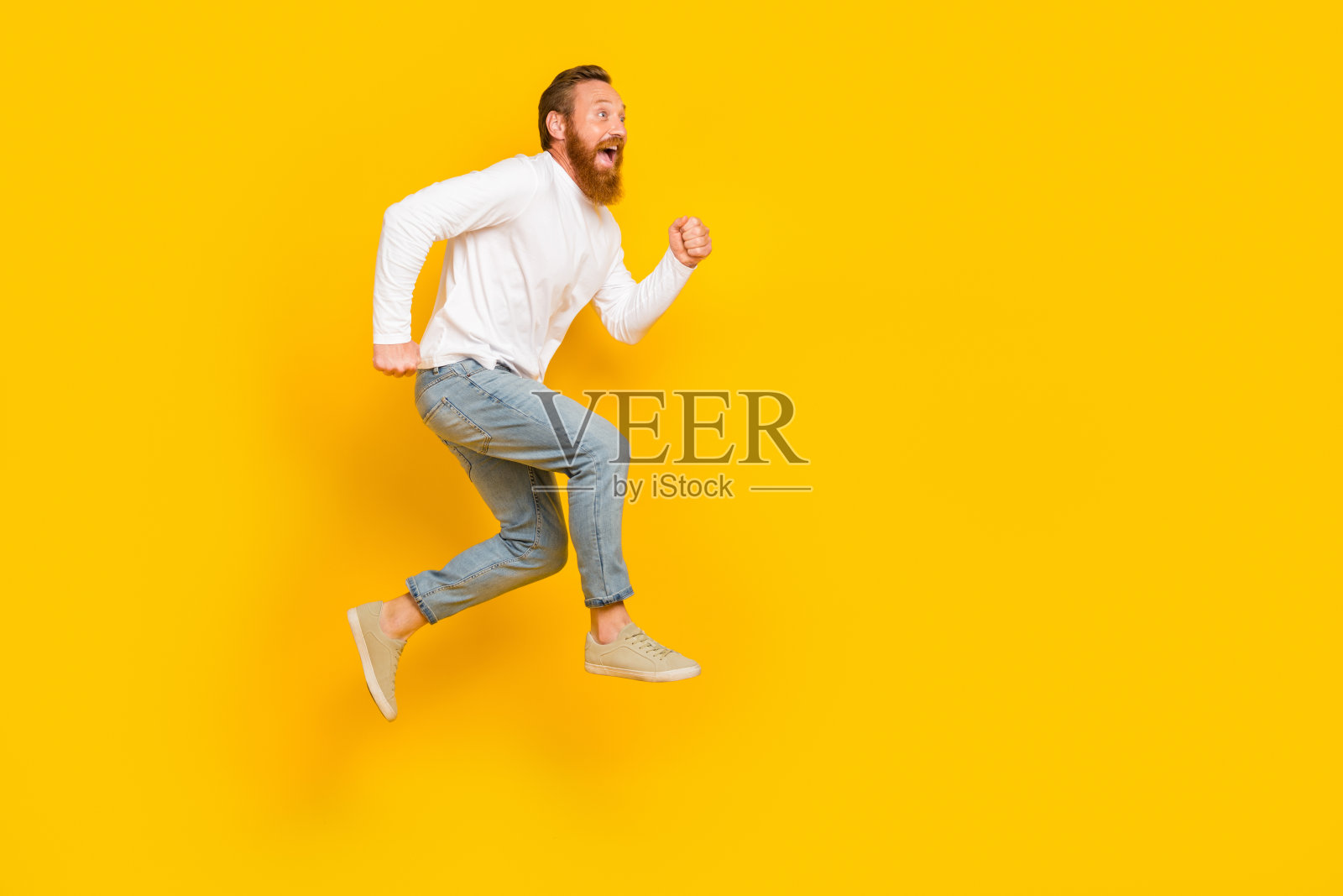 全身侧面照,留胡子的男人穿着促销服装,搭配牛仔裤和鞋子,背景为黄色。照片摄影图片