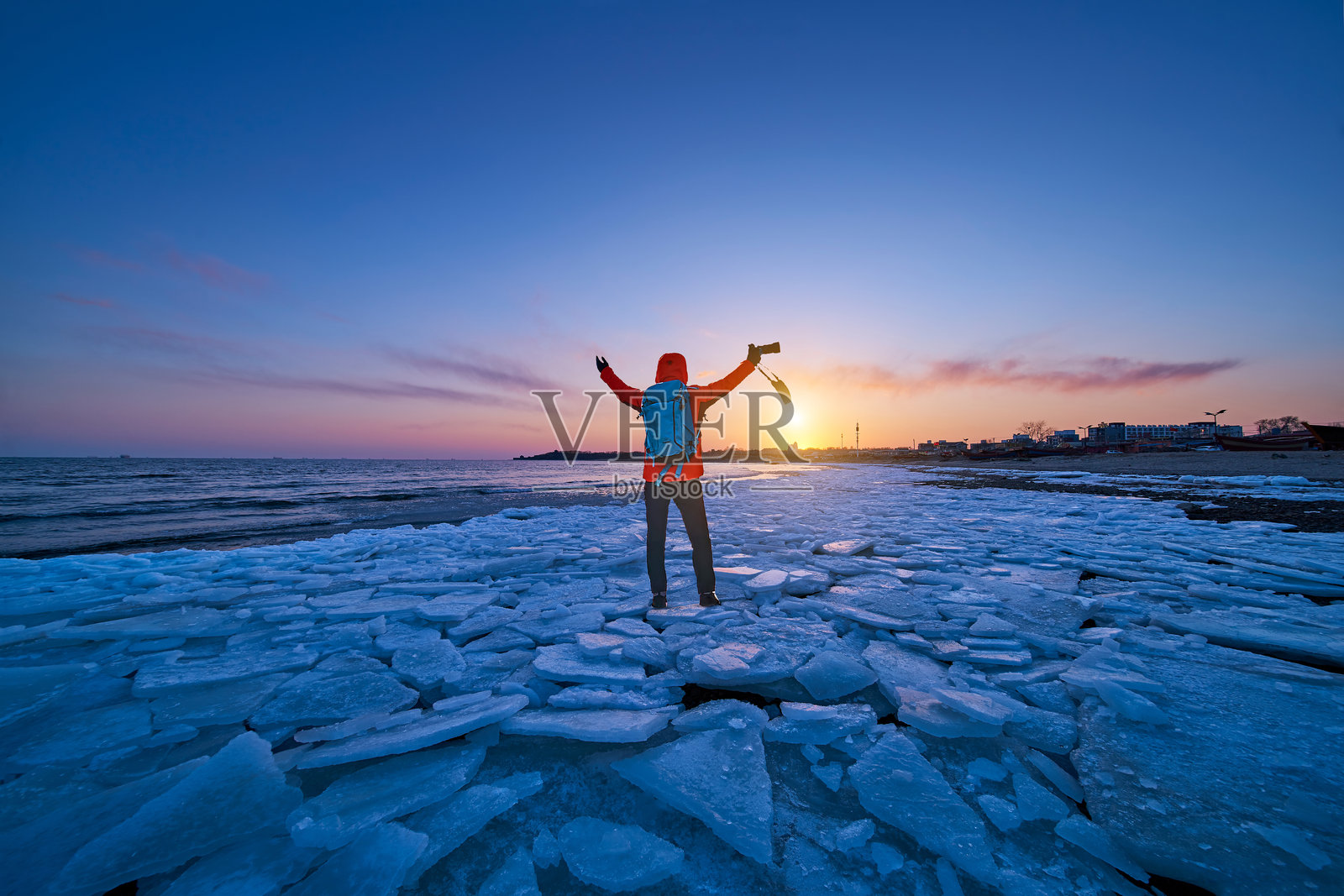 日落时分,女人背对着天空站在海滩上照片摄影图片