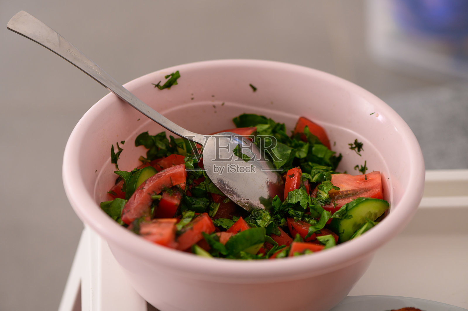 新鲜的花园沙拉,配有鲜艳的番茄、黄瓜和香草,置于阳光明媚的厨房环境中照片摄影图片