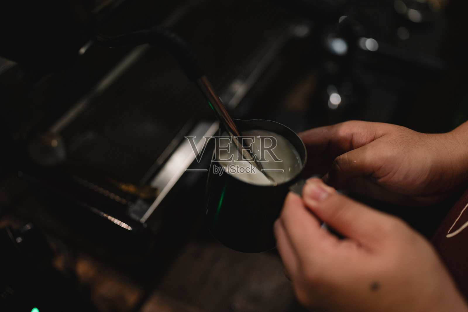 在迷人的咖啡馆里,机器发出嘶嘶声,蒸汽加热牛奶,制作出泡沫丰富的卡布奇诺,咖啡师小心翼翼地将其倒入杯中,创造出完美的热饮体验。照片摄影图片