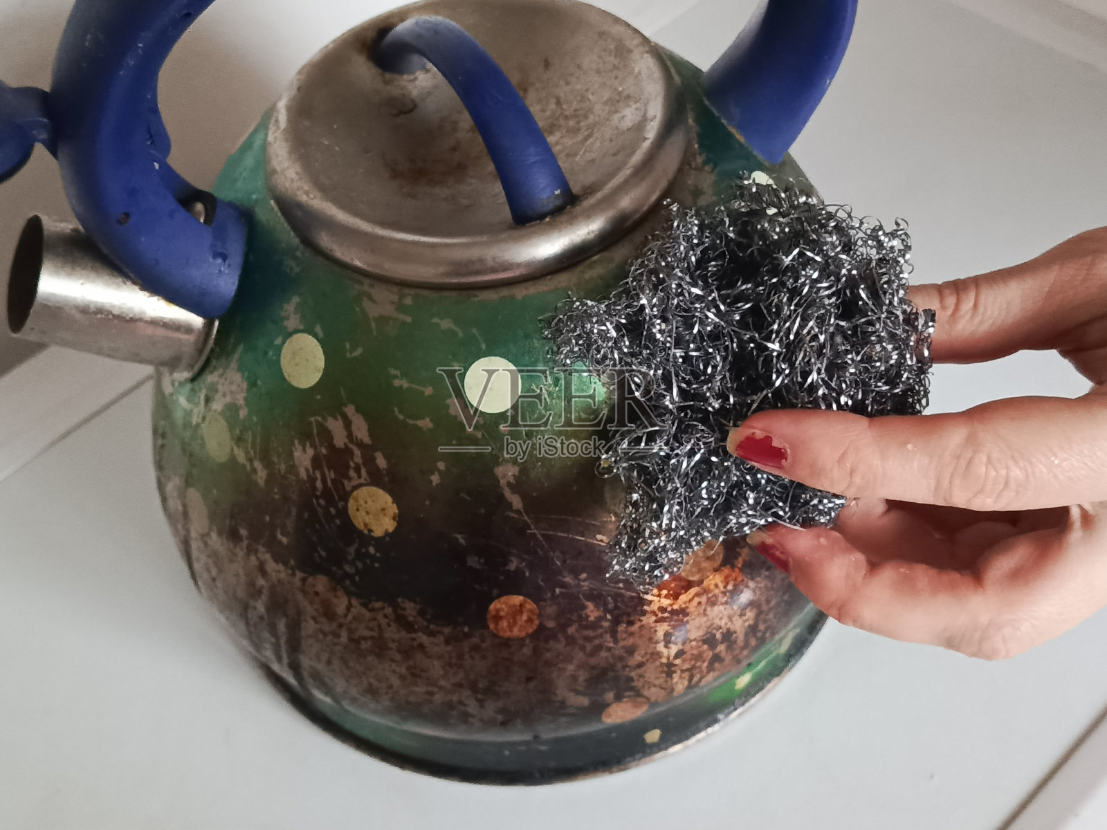 家庭主妇的手用铁刷清洁脏金属茶壶。洗涤脏碗碟。清洁服务。背景,留有文字空间。照片摄影图片