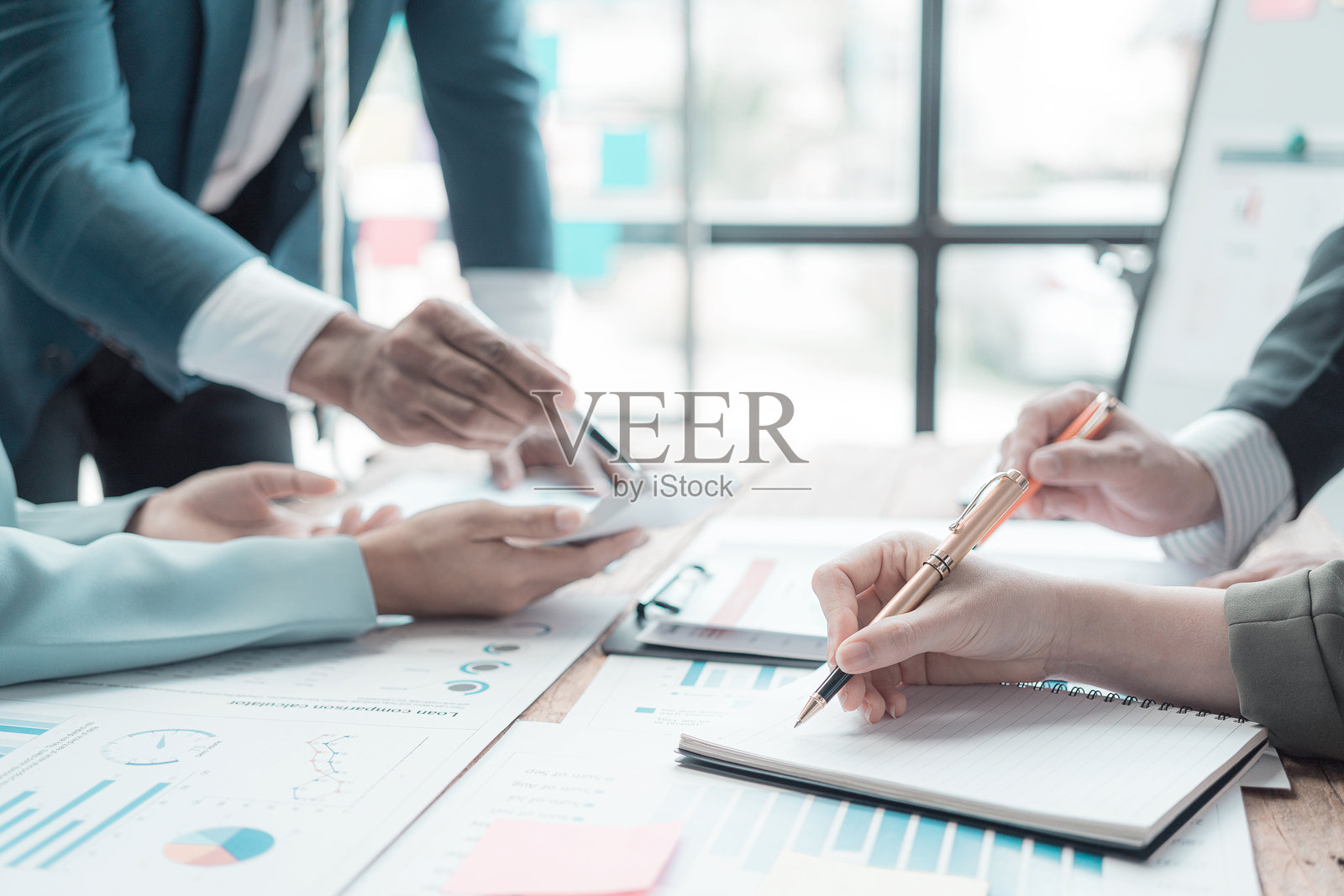 商界人士讨论显示成功团队合作的图表和图形。办公室内,一组商业同事在桌子旁分析财务数据的特写镜头。照片摄影图片